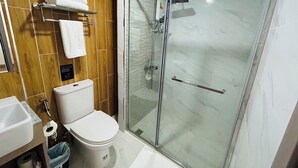 Une salle de bain moderne avec une douche à parois de verre, des toilettes et un lavabo.