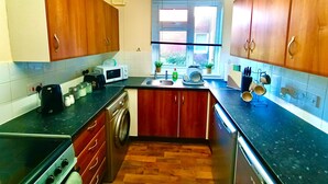 Una cocina compacta con armarios de madera, lavadora, microondas y fregadero.