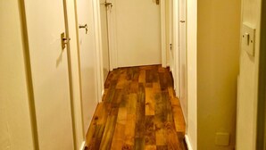 Un pasillo con suelo de madera y puertas blancas.