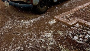 Ein alter, verwitterter Lastwagen steht auf einer unbefestigten Straße, im Hintergrund ein Backsteinhaus.