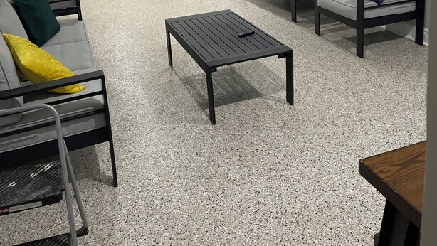Una sala moderna con sofá, mesa de centro y mesa de comedor. Cuenta con una zona de cocina con armarios y refrigerador.