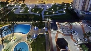Ein Resort mit Poolbereich, angelegten Gärten und Blick auf Strand und Meer im Abendlicht.
