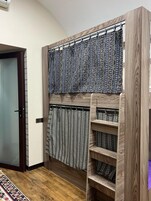 Una habitación con un armario de madera, cortinas estampadas y suelo de madera.