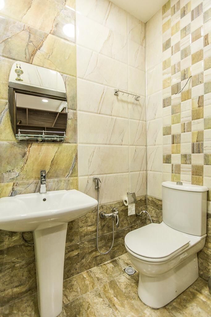A bathroom with a sink, toilet, and a towel dispenser.