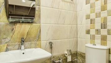A bathroom with a sink, toilet, and a towel dispenser.