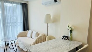 Una habitación de hotel moderna con una mesa de mármol, un sofá, una mesita redonda y una lámpara.