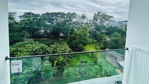 Un balcón con vistas a un parque verde exuberante y un río, con un letrero que dice 'No apoyarse'.