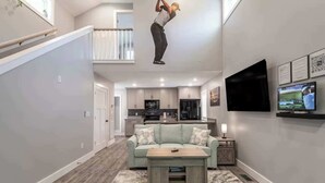 Ein modernes Wohnzimmer mit einer Couch, einem Couchtisch und einem an der Wand montierten Fernseher.