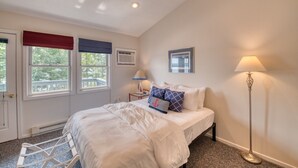 A bedroom with a bed, a window with a view, a bedside table with a lamp, and a radiator. - DePerrys On The Lake Waterfront Access to Lake Superior (Bayfield)