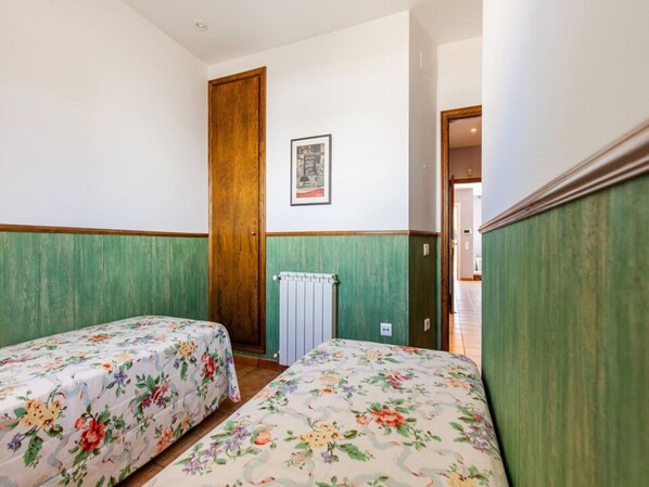 Una habitación con dos camas individuales, una puerta de madera, un radiador y un cuadro enmarcado en la pared.