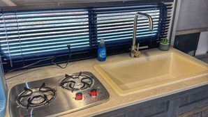 Une cuisine de taille réduite équipée d’une cuisinière à gaz, d’un évier et d’un four à micro-ondes.