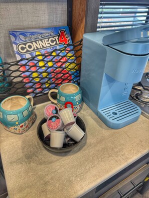 A kitchen counter with a coffee maker, mugs, and a Connect 4 game box. - Inlet Life Inn - Walk To Everything - (Murrells Inlet)