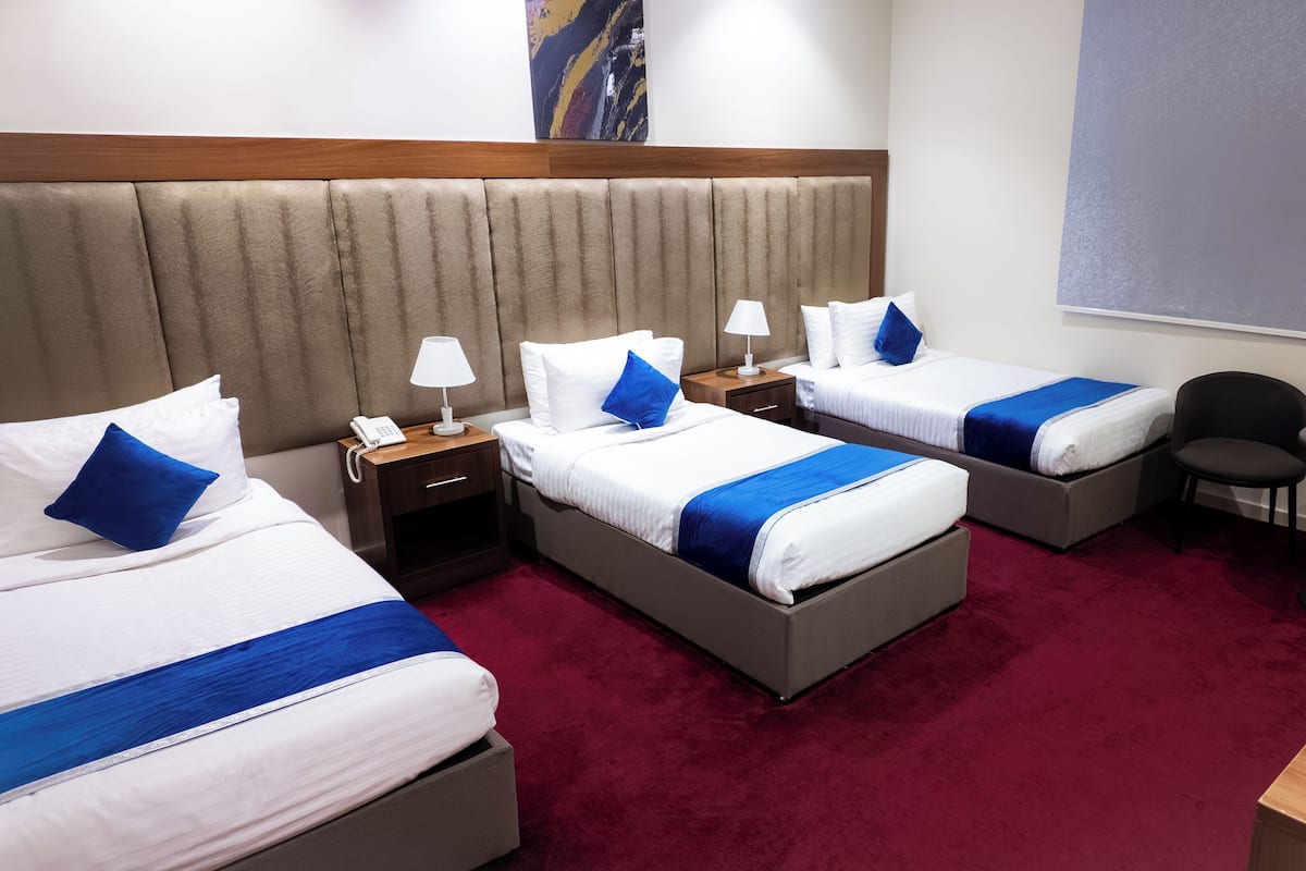 A hotel room with two beds, a desk, a chair, and a small table.