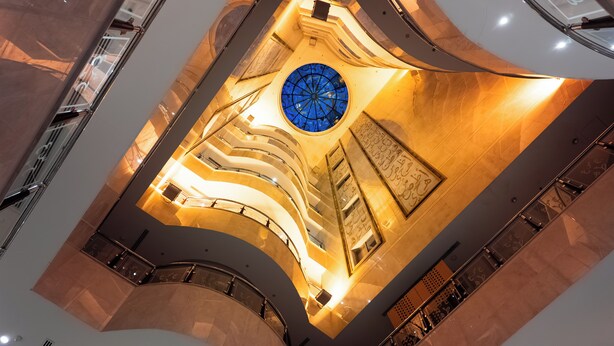 A multi-level atrium with a central blue stained glass dome, curved walls, and a modern design. - Maidan Al Bait (Makkah)
