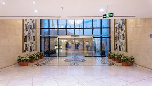 A hotel entrance with glass doors, potted plants, and a patterned floor. - Maidan Al Bait (Makkah)