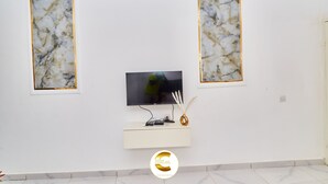 Una sala de estar moderna con un televisor de pantalla plana montado en una consola blanca, flanqueada por dos cuadros abstractos enmarcados.