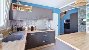 Una cucina moderna con mobili grigi, un piano di lavoro in legno e un piano cottura integrato.