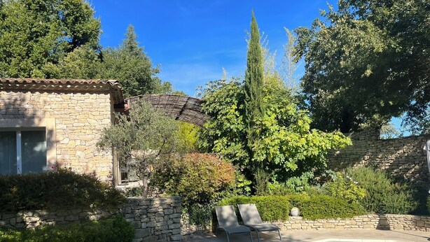 A stone building with a pool, surrounded by greenery and trees.