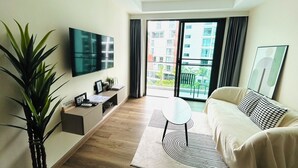 Een moderne woonkamer met een flatscreen televisie, een bank, een bijzettafeltje en een potplant.