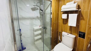 Een moderne badkamer met een douchecabine, toilet en een plank met toiletartikelen.