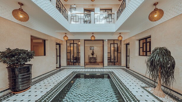 En rymlig innergård med en pool i mitten, en trappa och en balkong.
