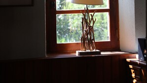 Una habitación con una ventana arqueada de madera, una lámpara sobre una mesa y un cuadro en la pared.