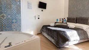 Een moderne hotelkamer met een groot bed, een flatscreen televisie, een badkuip en een betegelde muur met een patroon.
