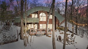 A cabin with a curved roof, wooden deck, and outdoor seating. - Sunset Burrow Retreat in Roscommon, MI - whole house, 3 bed, 2.5 bath! (Roscommon)