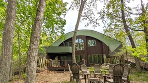 A cabin with a curved roof surrounded by trees. - Sunset Burrow Retreat in Roscommon, MI - whole house, 3 bed, 2.5 bath! (Roscommon)