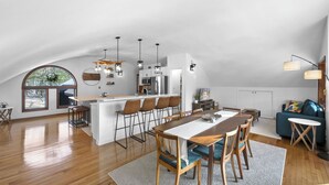 A spacious loft with a dining area, kitchen, and seating space. - Sunset Burrow Retreat in Roscommon, MI - whole house, 3 bed, 2.5 bath! (Roscommon)