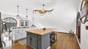 A modern kitchen with a central island, pendant lights, and a unique ceiling design. - Sunset Burrow Retreat in Roscommon, MI - whole house, 3 bed, 2.5 bath! (Roscommon)