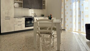 Una cocina moderna con comedor, que incluye una mesa y sillas blancas, horno integrado y una planta de cactus decorativa.