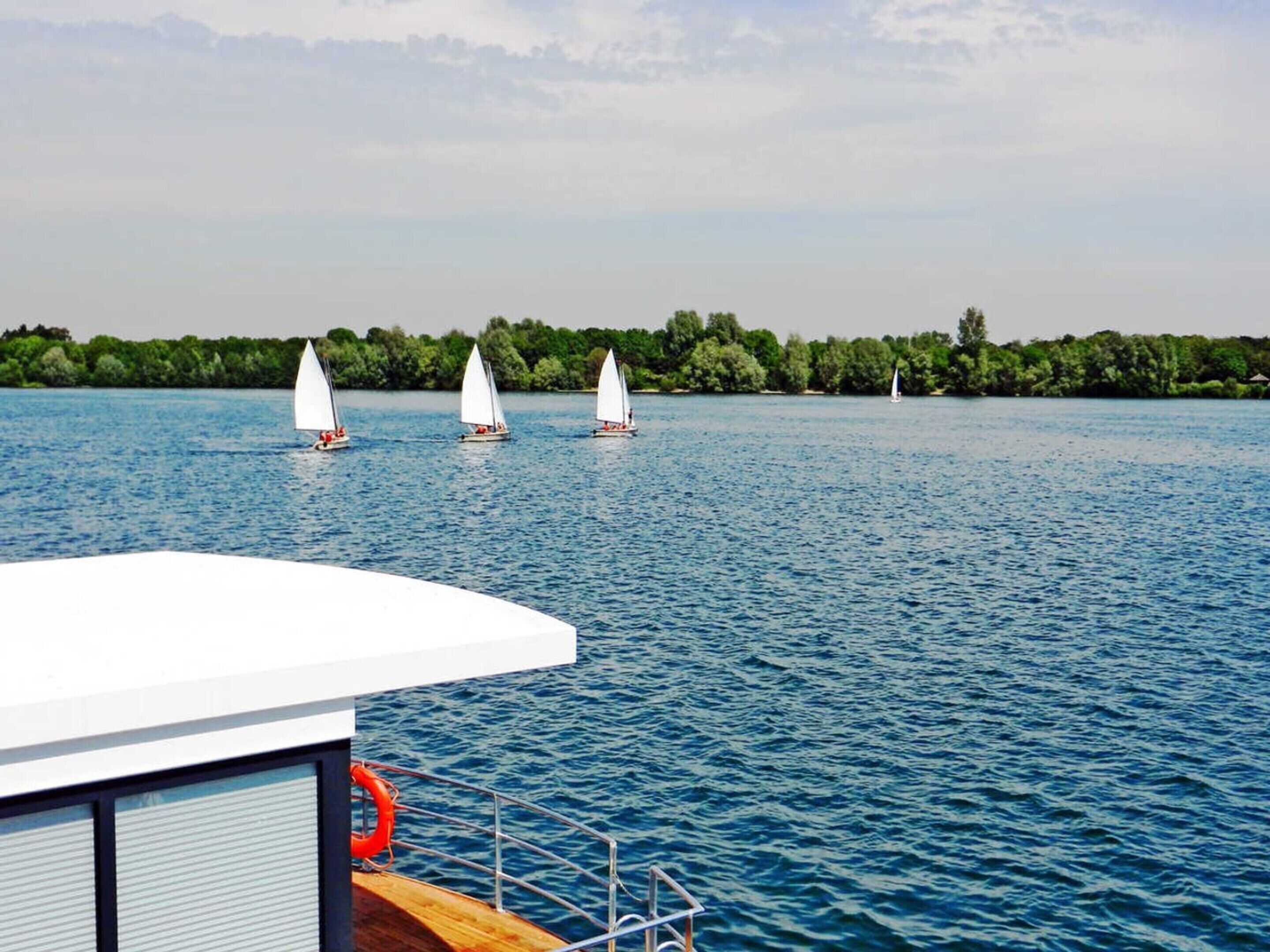 A calm lake with sailboats and a dock.