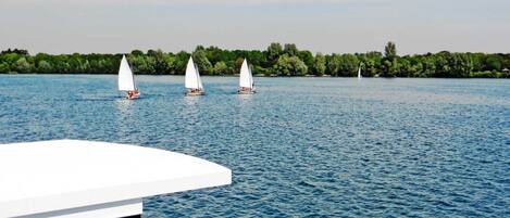 A calm lake with sailboats and a dock.