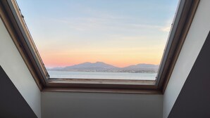 Un tragaluz con vista a una masa de agua y montañas distantes.