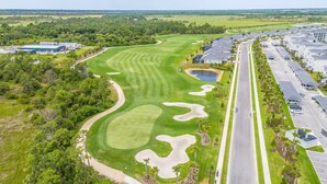 Eine Luftaufnahme eines Golfplatzes mit Parkplatz und Wohngebäuden.