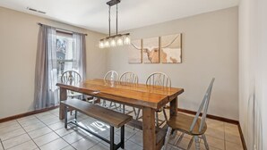 Un espace repas comprenant une table en bois, six chaises, un banc et un luminaire suspendu.