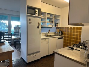A compact kitchen with white cabinets, a built-in microwave, a sink, and a gas stove.