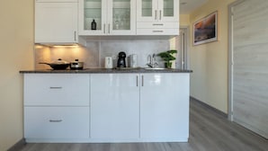 A modern kitchen with white cabinetry, a built-in stove, and a coffee maker. - One bedroom and one living room apartments in Estoril Beach Villas (Estoril)