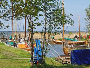 A dock with several boats, a grassy area, and a clear sky.