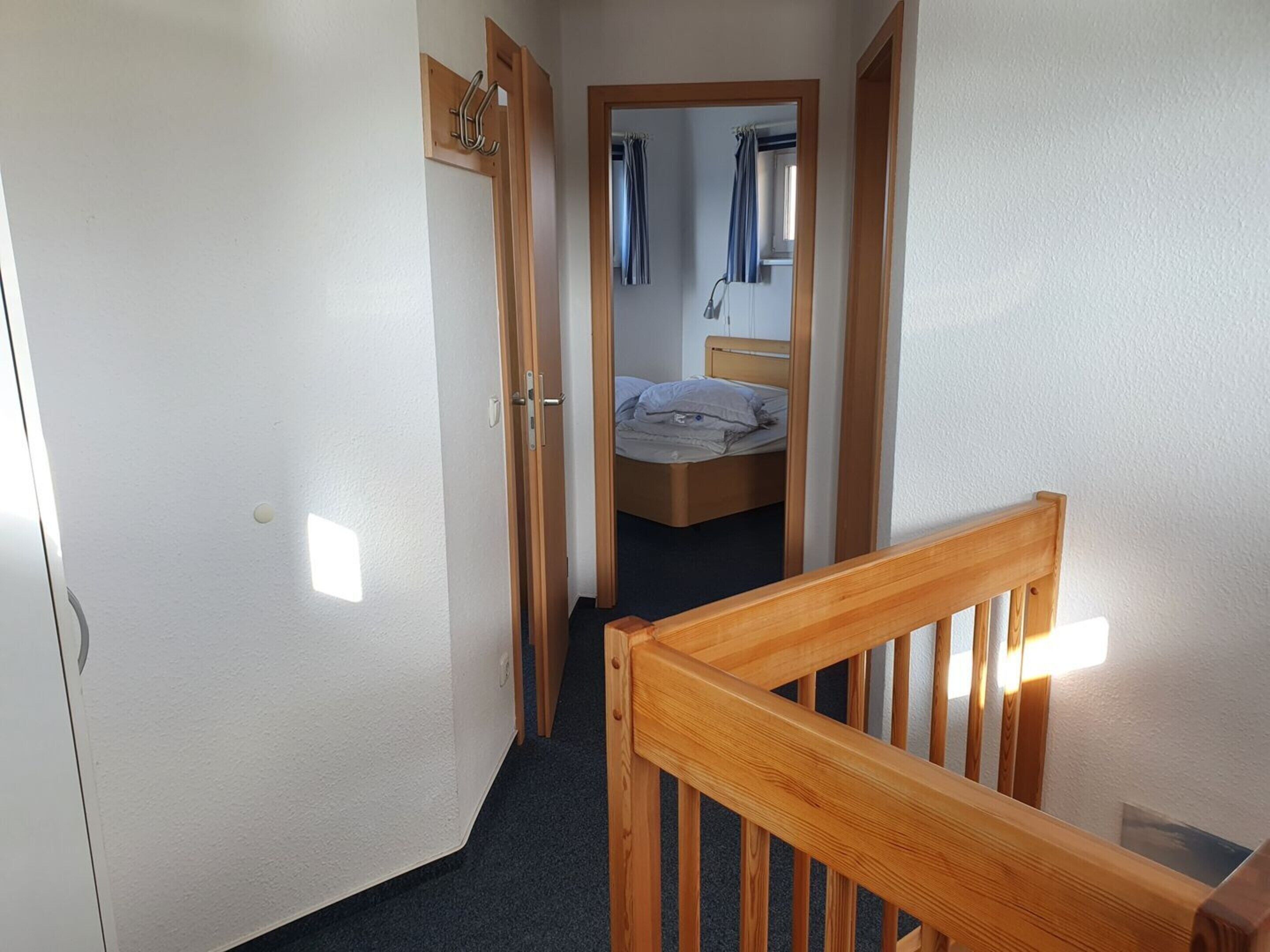 En smal hall med en trädörr och en säng i bakgrunden.