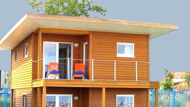 A two-story wooden houseboat with a balcony, outdoor seating, and a dock. - Hausboot in Barth am Barther Bodden (Barth)