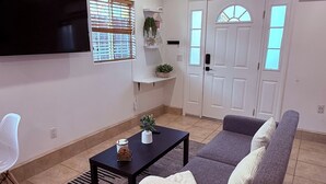 A living room with a sofa, a coffee table, a TV, a ceiling fan, and a door with windows. - Comfort Studio Near 101/405 (Los Angeles)