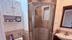 A bathroom with a glass-enclosed shower, a toilet, a sink, and a mirror. - Comfort Studio Near 101/405 (Los Angeles)