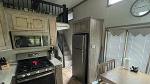 A kitchen with a stove, oven, microwave, refrigerator, and wooden cabinets. - Cozy 1 1/2-bedroom, 4 Bed Tiny House with Gas Heat/AC, WiFi ATV/Snowmobile (Park Falls)