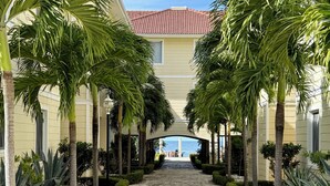 A pathway flanked by palm trees leading to a building with a red-tiled roof. - Hispaniola Beach 2-Bdrm 1st floor Condo with Oceanview & Private Beach in Sosúa (Sosúa)
