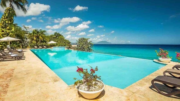 A poolside area with lounge chairs, a palm tree, and a view of the ocean. - Hispaniola Beach 2-Bdrm 1st floor Condo with Oceanview & Private Beach in Sosúa (Sosúa)