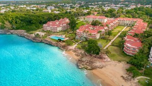 An aerial view of a coastal resort with multiple buildings, a beach, and a swimming pool. - Hispaniola Beach 2-Bdrm 1st floor Condo with Oceanview & Private Beach in Sosúa (Sosúa)