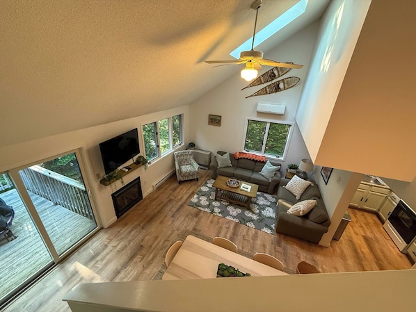 A spacious living room with a high ceiling, large windows, a fireplace, and a dining area. - Secluded 3-Bedroom North Conway Retreat – Family-Friendly, Close to Activities (Conway)