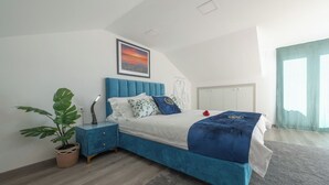 A bedroom with a blue bed, a nightstand, a potted plant, and a painting on the wall. - Apartment with terrace in Estoril seaside villa (Estoril)